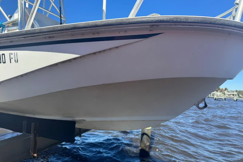 Slide: The Image of 1988 Boston Whaler Outrage 17 boat hull above water, docked on a sunny day. - 7