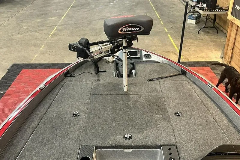 Slide: The Image of 2019 Triton 18 TrX boat deck with fishing seat and trolling motor in a garage setting. - 6