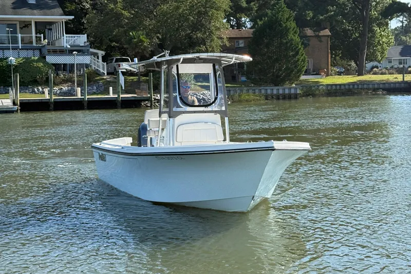 Slide: The Image of 2020 Parker 2100 Special Edition boat cruising on a calm river near waterfront homes. - 1
