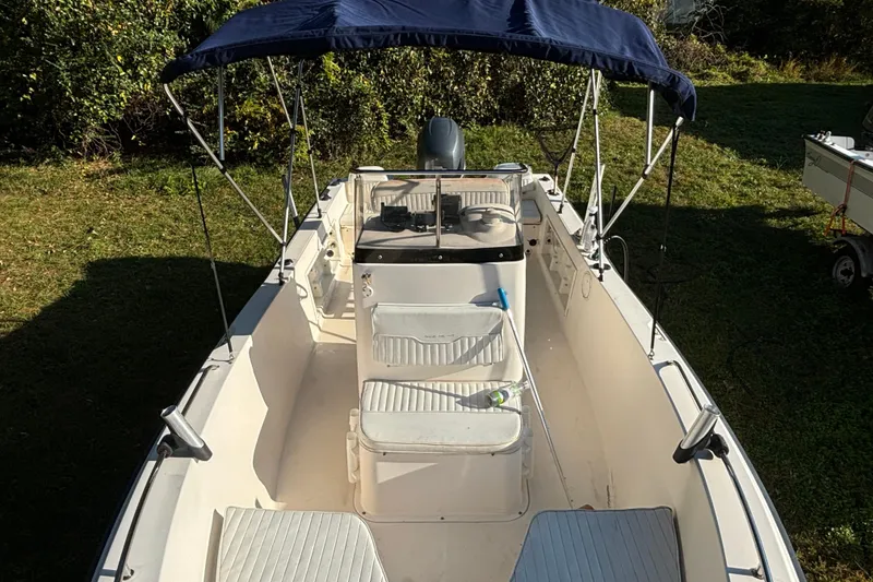 Slide: The Image of 2005 Sea Hunt Triton 202 boat with canopy, parked on grass. - 10