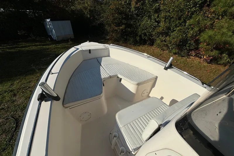 Slide: The Image of 2005 Sea Hunt Triton 202 boat interior with seating and storage, surrounded by greenery. - 14