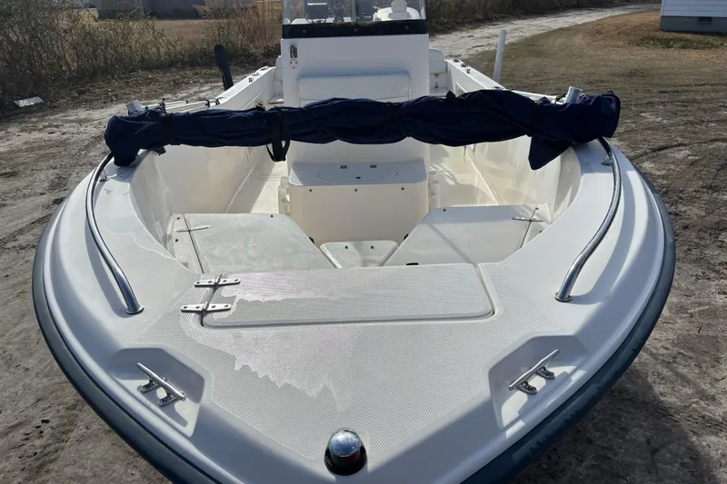 Slide: The Image of 2005 Sea Hunt Triton 202 boat, white interior, bow view, parked on sandy ground. - 9