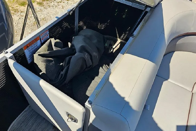 Slide: The Image of Open storage compartment on a 2023 Bennington 21 SLX boat with seating and fabric inside. - 23