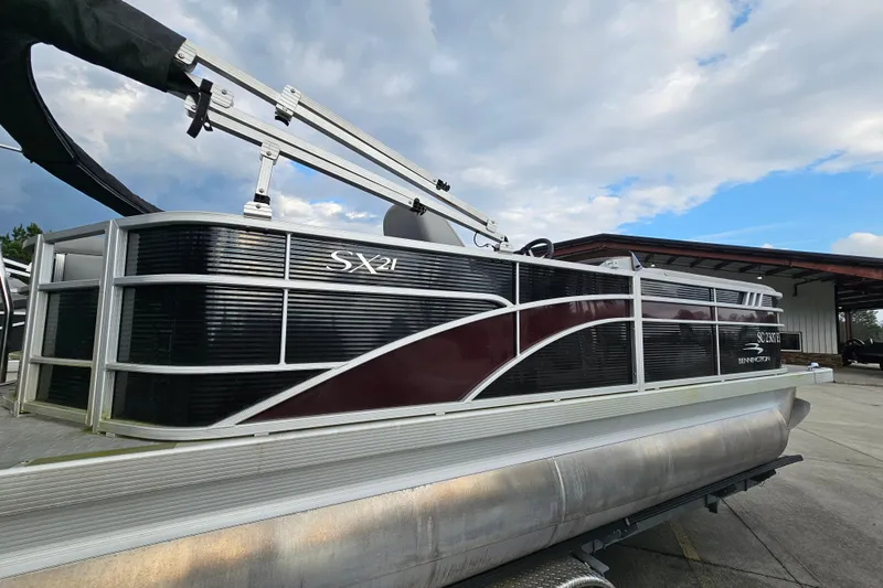 Slide: The Image of 2023 Bennington 21 SLX pontoon boat with sleek design under a cloudy sky. - 5
