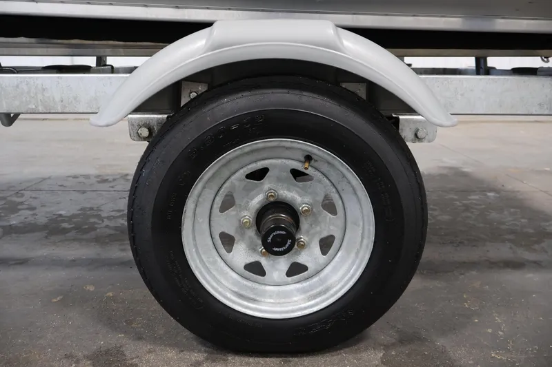 Slide: The Image of 2022 Lund SSV-16 Tiller trailer wheel with metal rim and tire in a garage. - 27