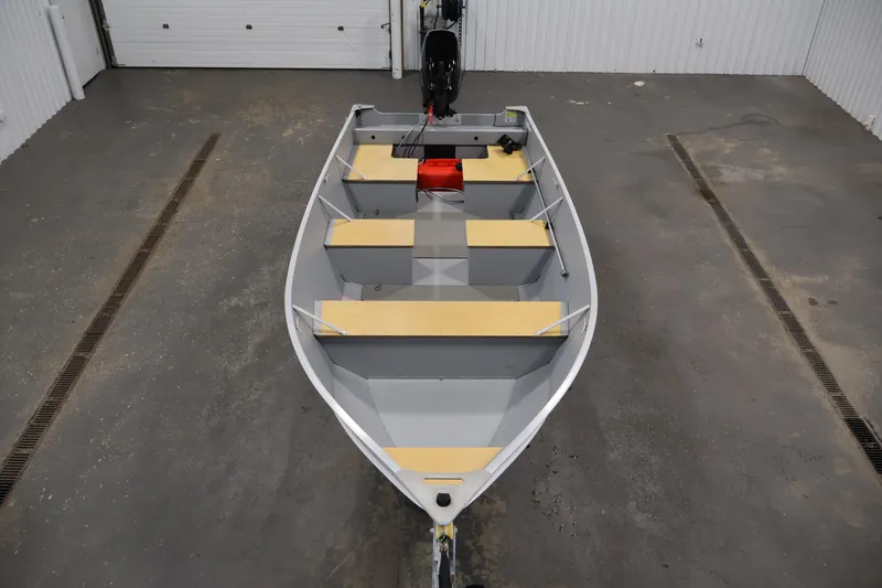 Slide: The Image of 2022 Lund SSV-16 Tiller boat in a garage, showcasing interior seating and motor. - 9