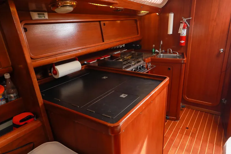 Slide: The Image of 1988 Grand Soleil 46 Jezequel yacht kitchen with stove, sink, and wooden cabinetry. - 14