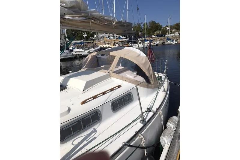 Slide: The Image of 1975 Mirage Yachts 27 sailboat docked at a marina, featuring a beige canopy. - 7