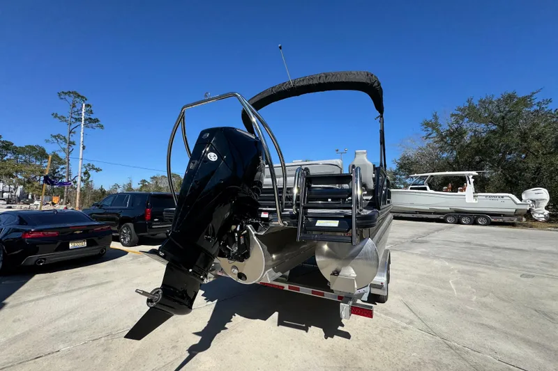 Slide: The Image of 2026 Bennington 22 MSB pontoon boat with outboard motor on trailer, sunny day. - 11
