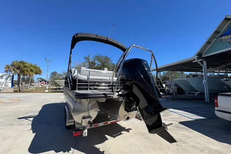Slide: The Image of 2026 Bennington 22 MSB pontoon boat with outboard motor, parked outdoors under clear blue sky. - 13