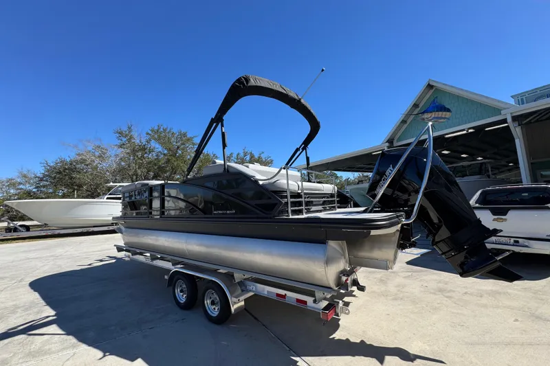 Slide: The Image of 2026 Bennington 22 MSB pontoon boat on trailer, parked outdoors under clear blue sky. - 14