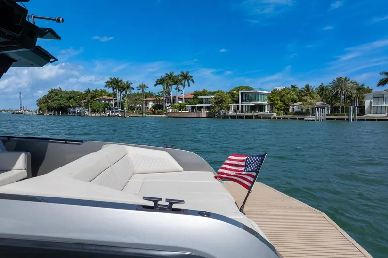 Slide: The Image of Luxurious 2022 Vanquish VQ40 yacht cruising near waterfront homes, featuring an American flag. - 45