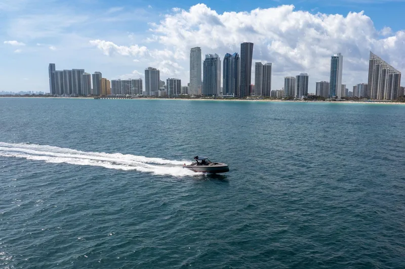 Slide: The Image of 2022 Vanquish VQ40 yacht cruising near a city skyline under a partly cloudy sky. - 53