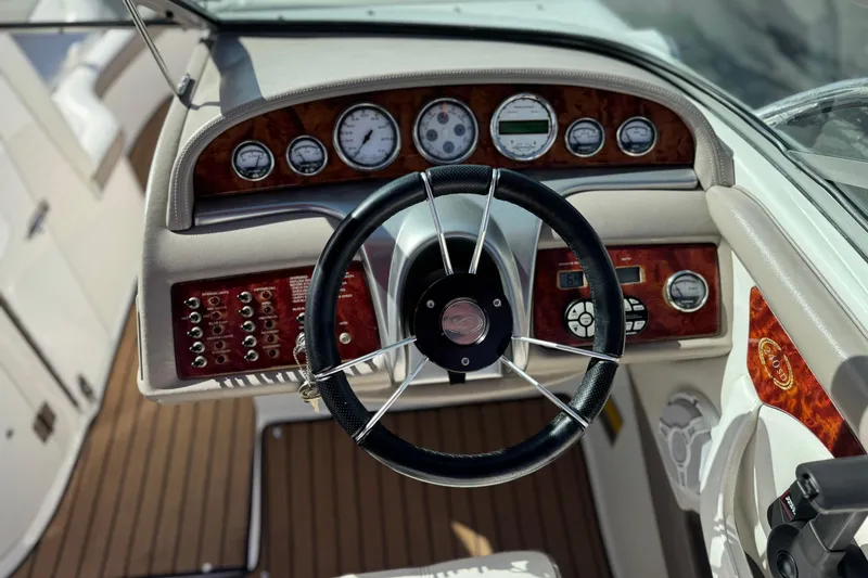 Slide: The Image of Steering wheel and dashboard of a 2004 Cobalt 240SD boat, featuring wood accents. - 33