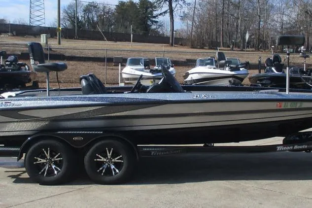 Slide: The Image of 2011 Triton 21XS Elite boat on trailer, parked outdoors with other boats in background. - 1