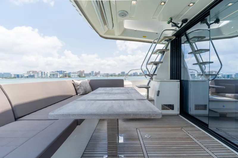 Slide: The Image of Prestige 520 Flybridge 2019 yacht with outdoor seating and dining area, city skyline in background. - 29