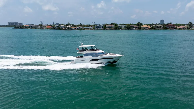 Slide: The Image of 2019 Prestige 520 Flybridge yacht cruising on a sunny day near coastal homes. - 43