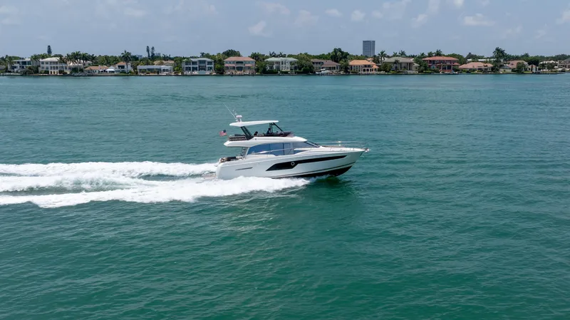 Slide: The Image of 2019 Prestige 520 Flybridge yacht cruising on a sunny day near coastal homes. - 44