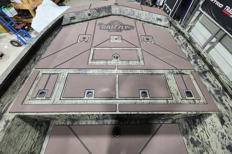 Slide: The Image of 2026 Tracker Grizzly 2072 CC boat deck with storage compartments and camo design. - 11