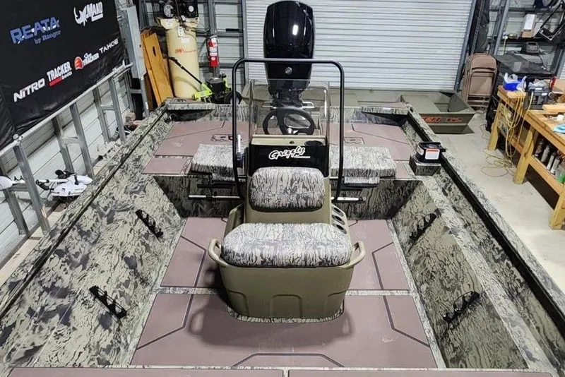 Slide: The Image of 2026 Tracker Grizzly 2072 CC boat in a garage, featuring camo design and central console. - 7