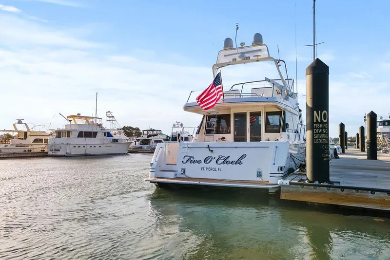 Slide: The Image of 2000 West Bay 58 Sonship yacht docked with American flag, calm marina setting. - 49