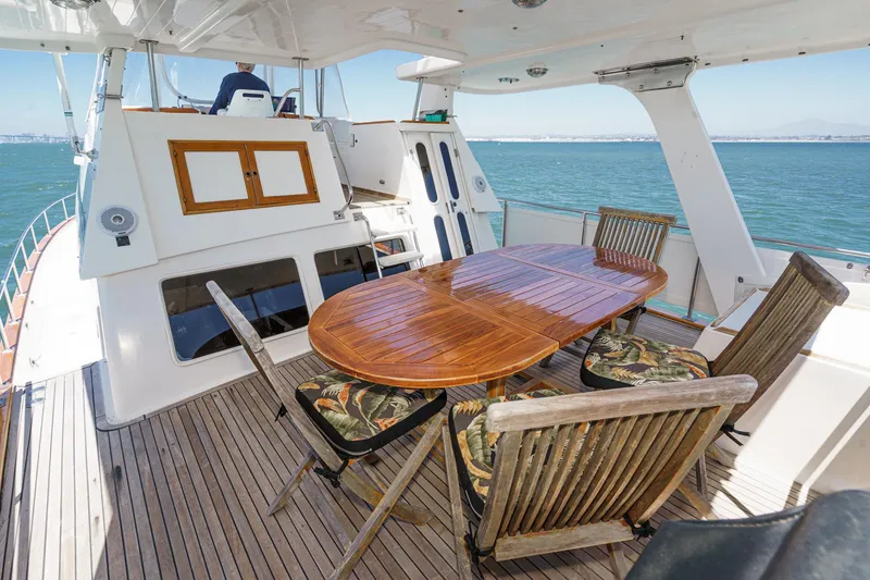 Slide: The Image of 1986 Offshore Yachts Cockpit Motoryacht with wooden table and chairs on deck. - 4