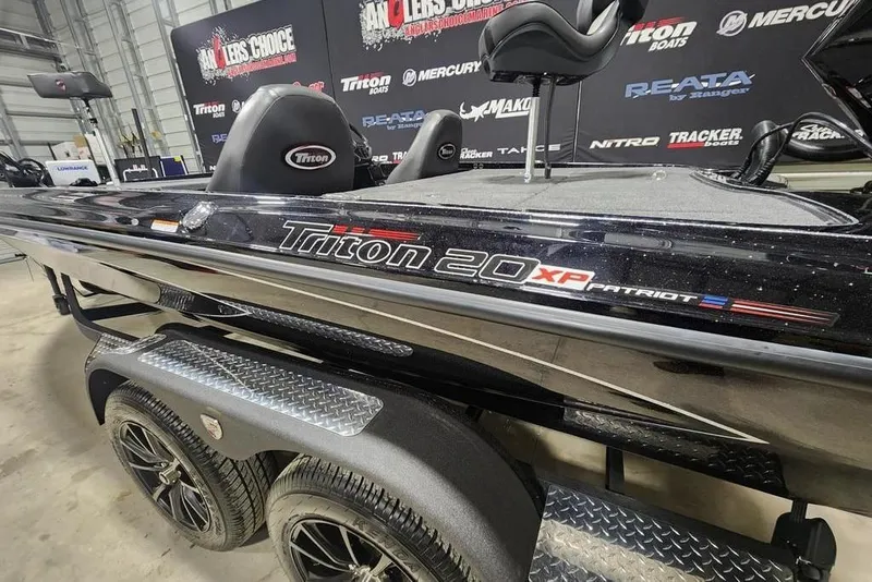 Slide: The Image of 2026 Tracker Grizzly 12 Jon boat in showroom, featuring Triton 20 XP Patriot branding. - 14