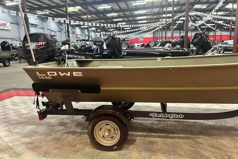 Slide: The Image of 2024 Lowe L1448 Jon boat on trailer in showroom with Mercury outboard. - 12
