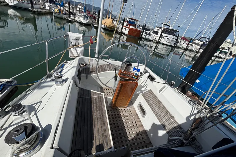 Slide: The Image of 1986 Beneteau First 375 sailboat cockpit in marina, showcasing steering wheel and deck layout. - 2