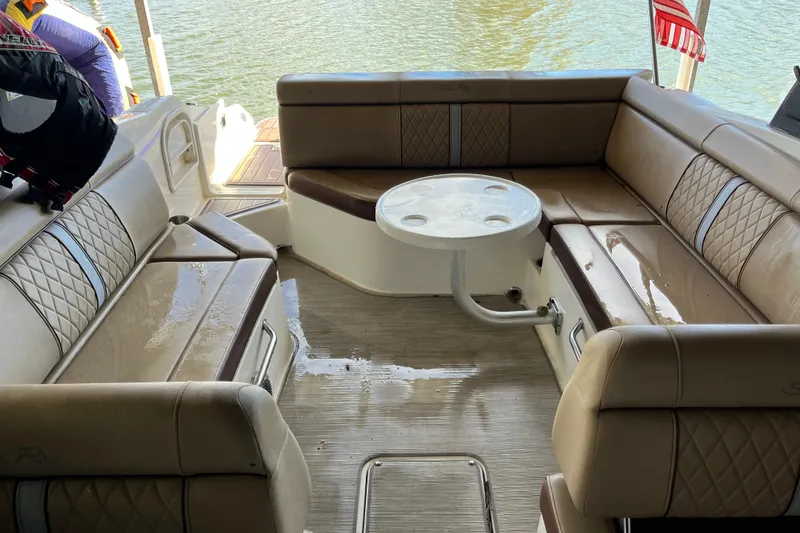 Slide: The Image of 2016 Sea Ray 270 Sundeck interior with beige seating and round table on the water. - 18