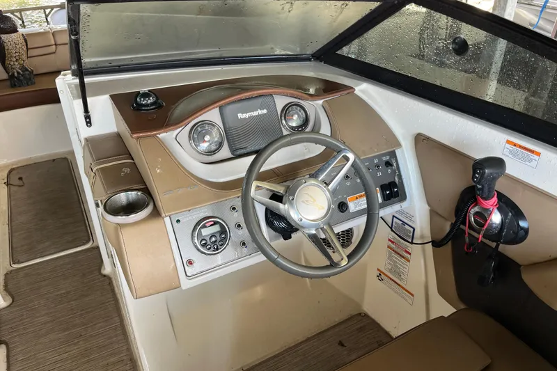 Slide: The Image of 2016 Sea Ray 270 Sundeck helm with steering wheel, Raymarine display, and control panel. - 19