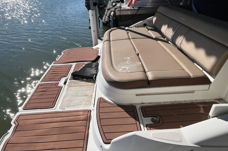 Slide: The Image of 2016 Sea Ray 270 Sundeck boat with cushioned seating and wooden deck by the water. - 4