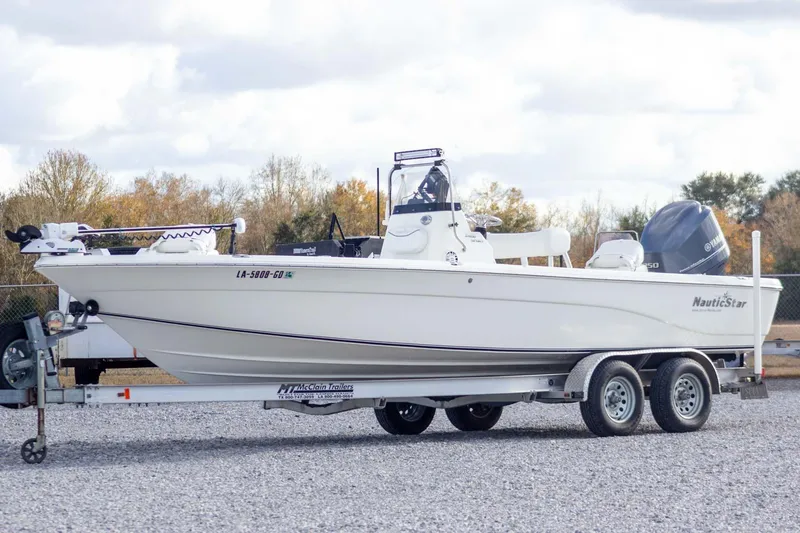 Slide: The Image of 2014 NauticStar 2400 Sport boat on trailer, parked outdoors. - 1