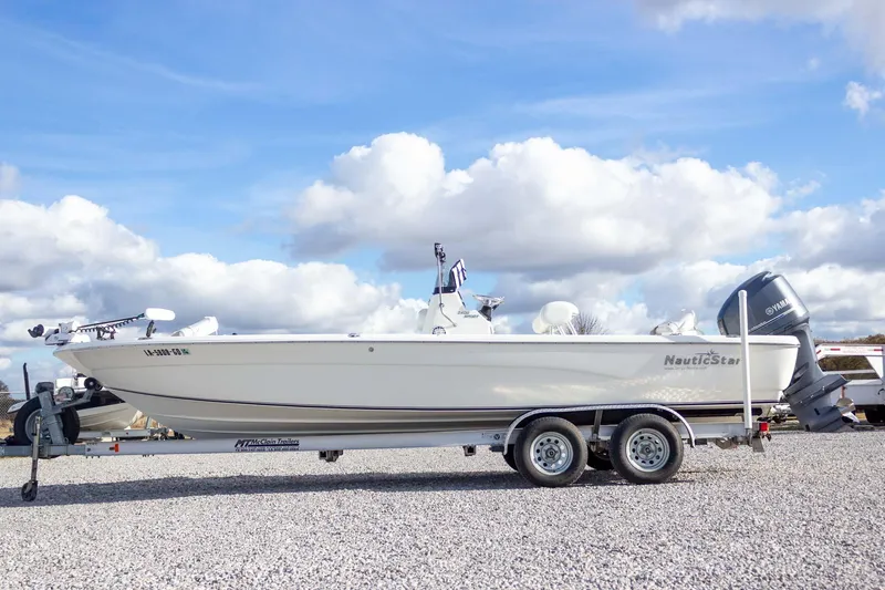 Slide: The Image of 2014 NauticStar 2400 Sport boat on trailer under a blue sky with clouds. - 11