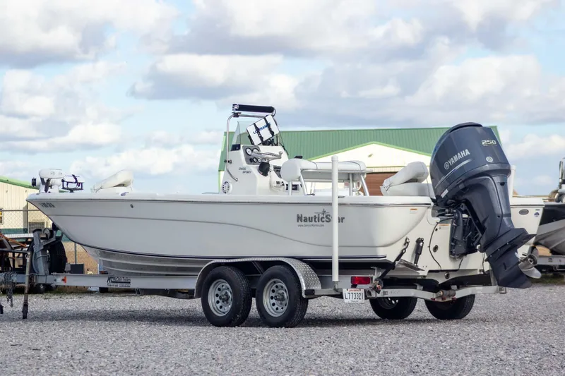 Slide: The Image of 2014 NauticStar 2400 Sport boat on trailer with Yamaha engine, parked outdoors. - 2