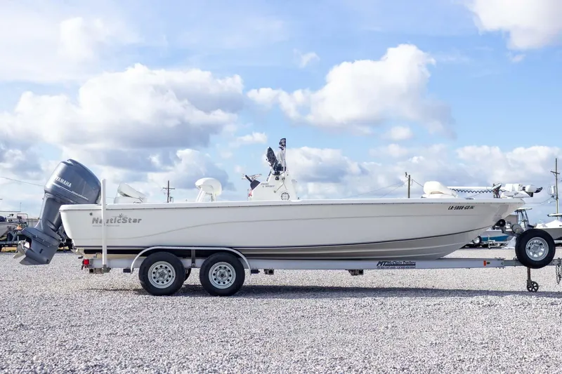 Slide: The Image of 2014 NauticStar 2400 Sport boat on trailer under cloudy sky. - 7