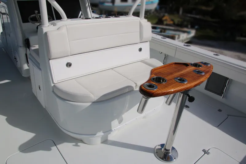 Slide: The Image of 2022 Yellowfin 39 Offshore boat interior with cushioned seating and wooden cup holder table. - 18