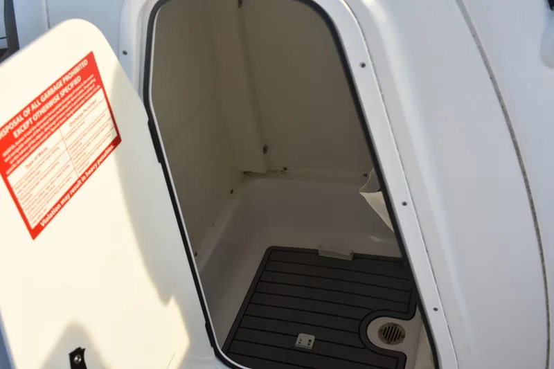 Slide: The Image of 2021 Tidewater 232 LXF boat storage compartment with drainage and warning label. - 17