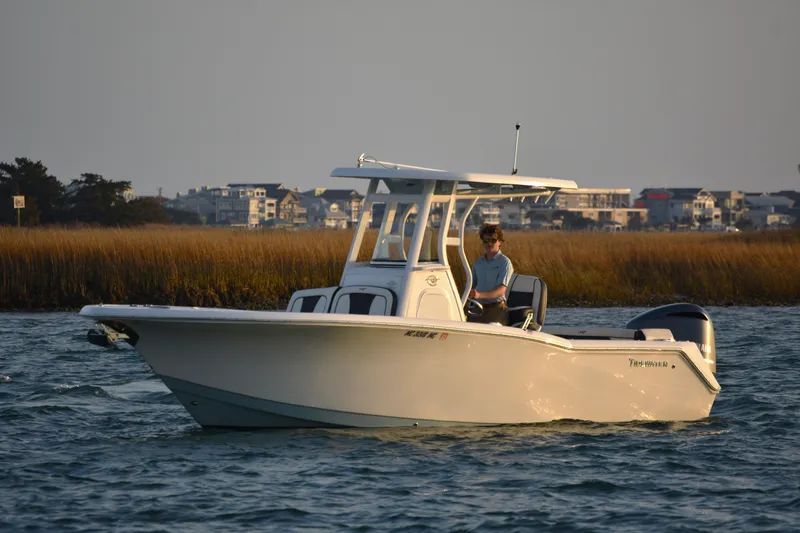 Slide: The Image of 2021 Tidewater 232 LXF boat cruising on calm water near coastal homes. - 3