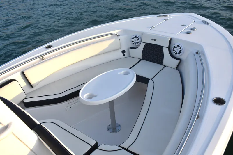 Slide: The Image of 2021 Tidewater 232 LXF boat interior with cushioned seating and table on calm water. - 7