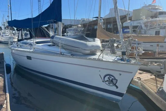 Slide: The Image of 1995 Hunter Legend 40.5 sailboat docked at marina with blue canopy and inflatable dinghy. - 1