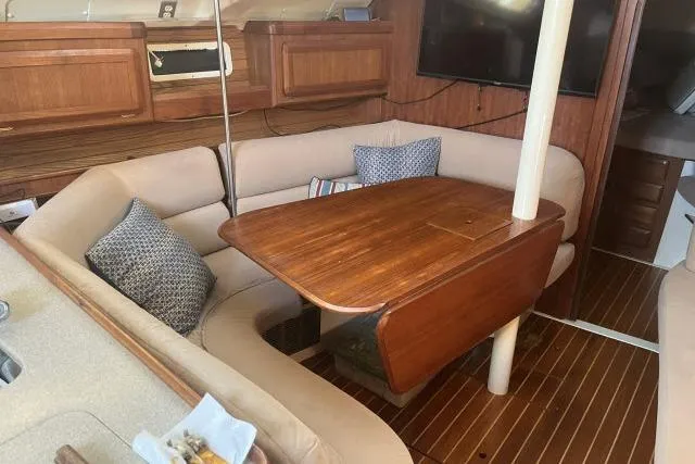Slide: The Image of 1995 Hunter Legend 40.5 yacht interior with wooden table and cushioned seating. - 3