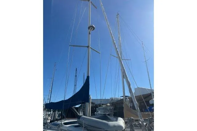 Slide: The Image of 1995 Hunter Legend 40.5 sailboat with blue cover docked at marina under clear sky. - 31
