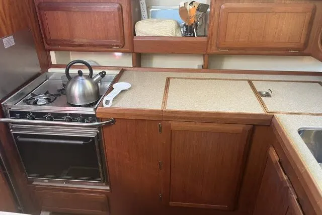 Slide: The Image of 1995 Hunter Legend 40.5 yacht kitchen with stove, kettle, and wooden cabinetry. - 5
