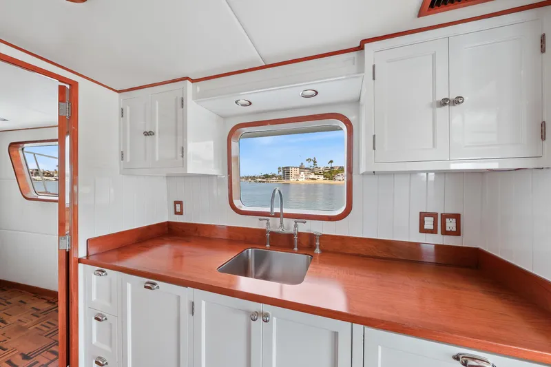 Slide: The Image of 1970 Hargrave Yachtfisher kitchen with wooden countertops, white cabinets, and ocean view window. - 31