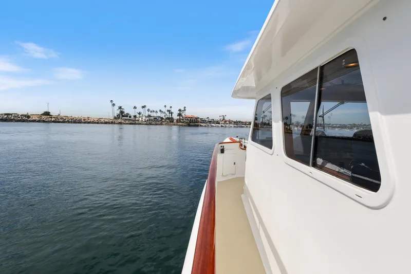 Slide: The Image of 1970 Hargrave Yachtfisher cruising near a coastal harbor with palm trees. - 65
