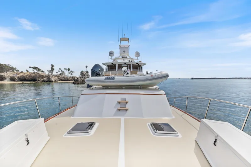 Slide: The Image of 1970 Hargrave Yachtfisher on calm waters, featuring a spacious deck and tender boat. - 68