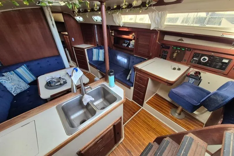 Slide: The Image of 1988 36 Catalina MK I yacht interior with wood finish, blue seating, and kitchen area. - 9