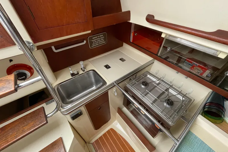 Slide: The Image of 1985 Canadian Sailcraft CS 30 yacht kitchen with stove, sink, and storage. - 25