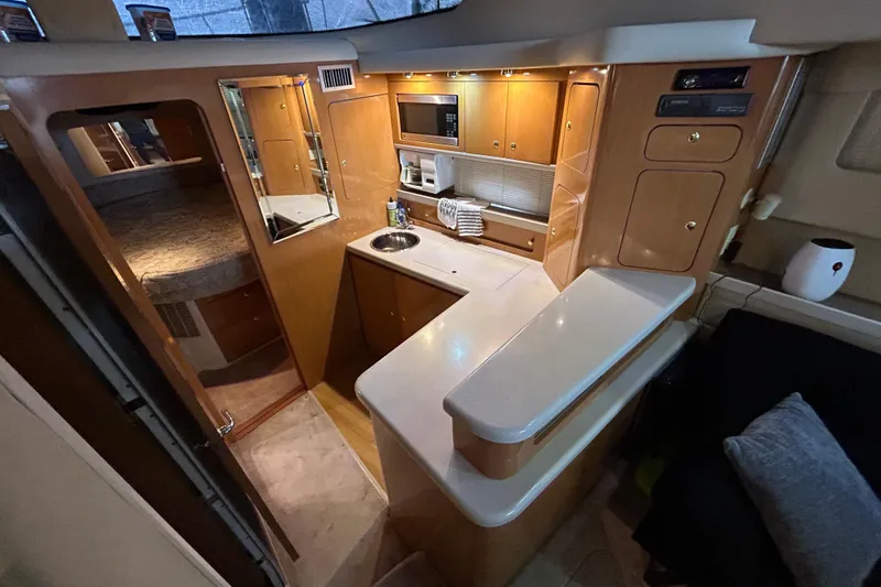 Slide: The Image of Interior of 2001 Regal Commodore 3880 yacht, featuring a compact kitchen and cozy cabin space. - 21